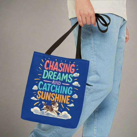 Blue tote bag with 'Chasing Dreams and Catching Sunshine' text and a dog illustration
